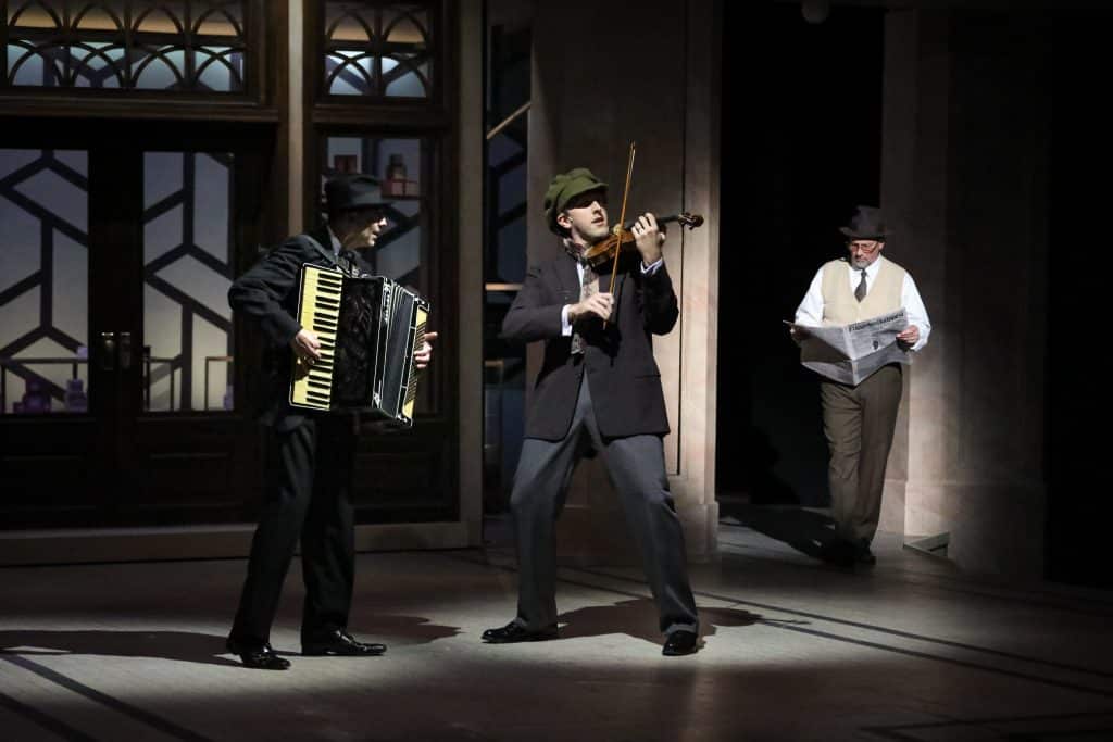 As part of the new orchestration, Mark Hartman and Dan Toot play the accordion and violin, respectively, in the prologue, as Jeffrey Blair Cornell's Sipos reads the newspaper in PlayMakers Repertory Company's production of SHE LOVES ME. (HuthPhoto)